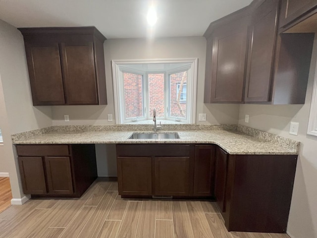 kitchen featuring light wood-type flooring, a sink, and dark brown cabinets