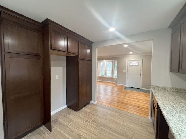 kitchen with dark brown cabinetry, wood tiled floor, baseboards, and light countertops