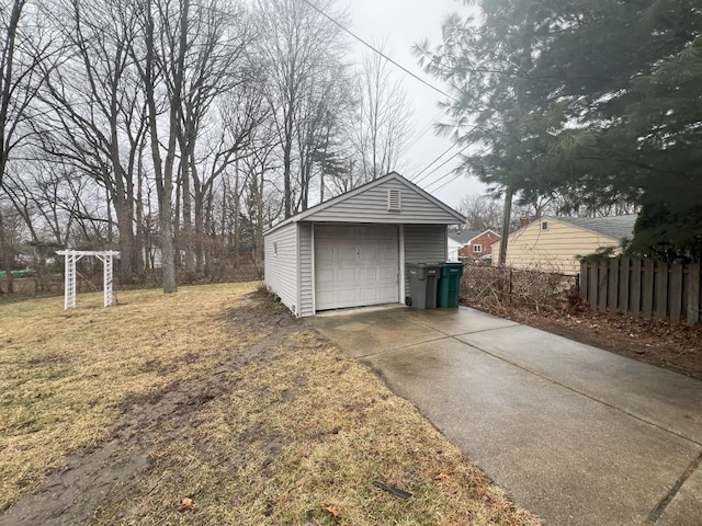 detached garage featuring fence and concrete driveway