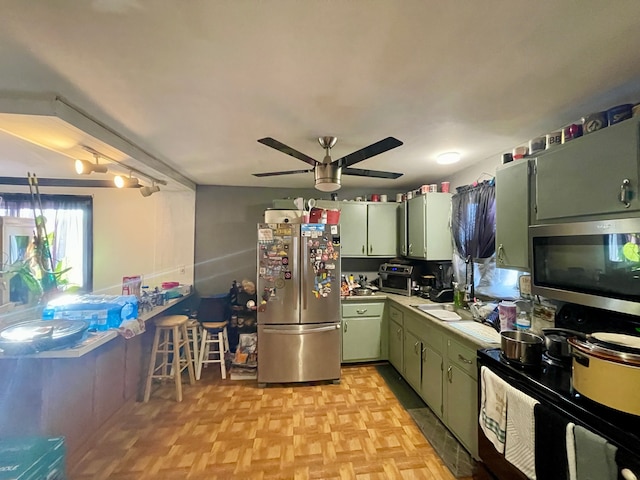 kitchen with light countertops, green cabinets, appliances with stainless steel finishes, a sink, and ceiling fan