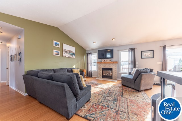 living area with lofted ceiling, light wood finished floors, a fireplace, and baseboards