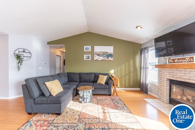 living room featuring lofted ceiling, a brick fireplace, baseboards, and wood finished floors