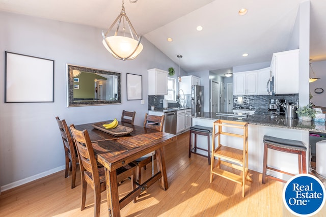 dining room with vaulted ceiling, light wood finished floors, recessed lighting, and baseboards