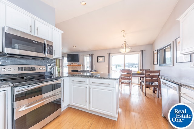 kitchen with a peninsula, light wood-type flooring, white cabinetry, and stainless steel appliances