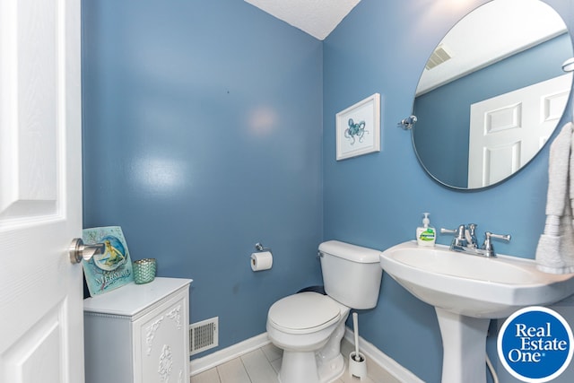 half bath featuring toilet, baseboards, and visible vents