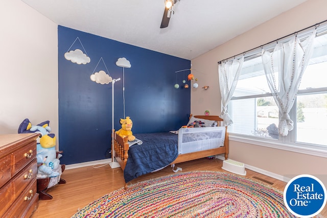 bedroom featuring visible vents, ceiling fan, baseboards, and wood finished floors