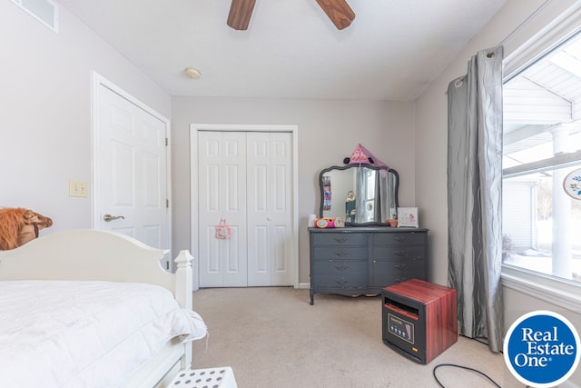 bedroom with a closet, light colored carpet, ceiling fan, and visible vents