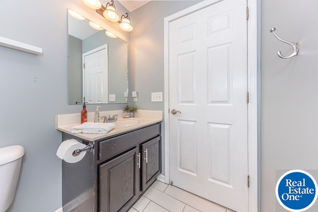 bathroom with toilet, vanity, and tile patterned floors