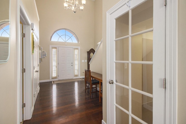 foyer entrance featuring dark wood-style floors, baseboards, a high ceiling, and a chandelier