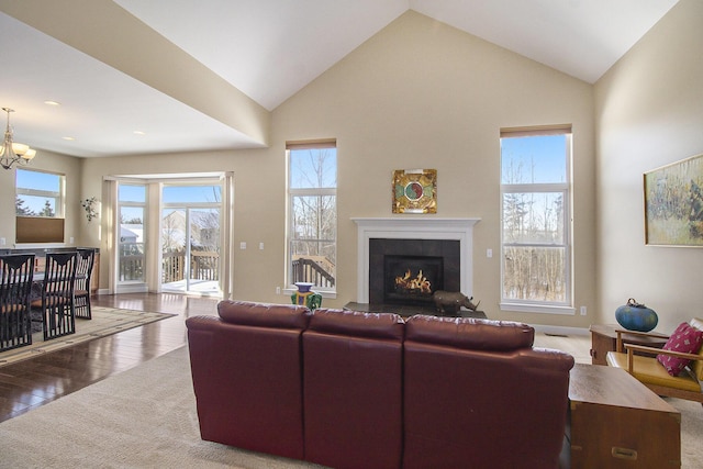 living room featuring high vaulted ceiling, a chandelier, wood finished floors, and a tile fireplace