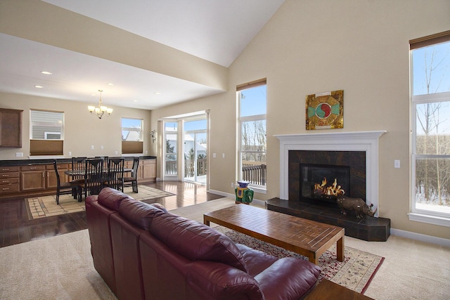 carpeted living area with high vaulted ceiling, recessed lighting, a tiled fireplace, a chandelier, and baseboards