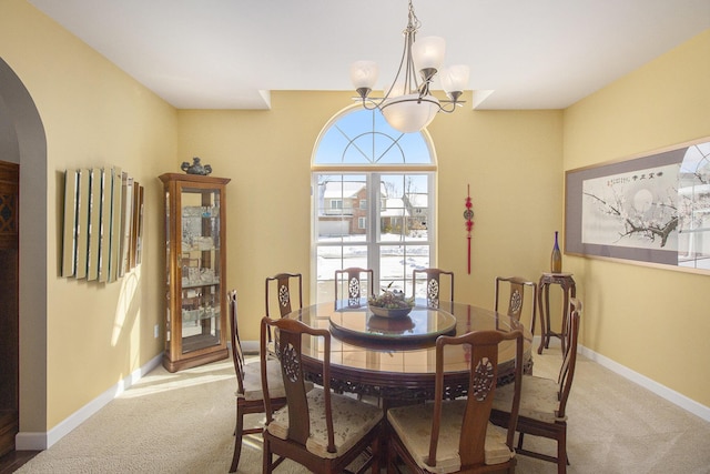 dining space with arched walkways, light carpet, and baseboards