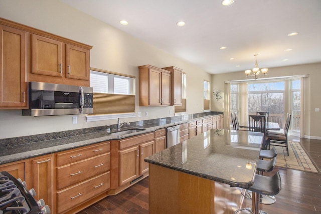 kitchen featuring a breakfast bar, pendant lighting, dark wood finished floors, stainless steel appliances, and a sink