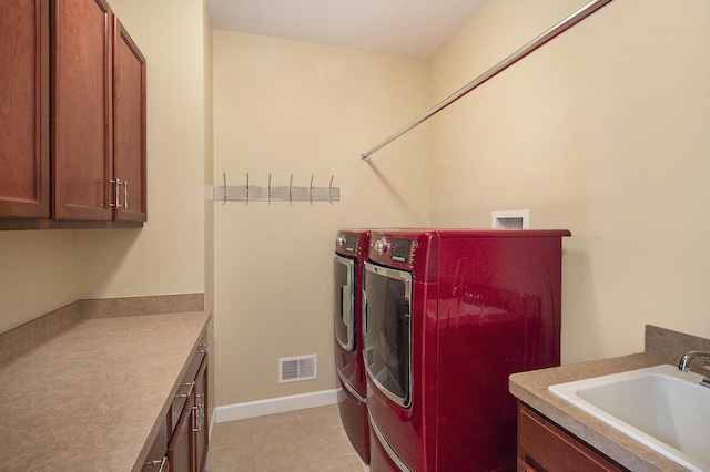 washroom with cabinet space, visible vents, washer and dryer, and a sink