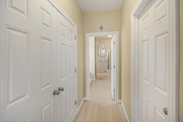 hallway featuring light tile patterned floors, light colored carpet, and baseboards