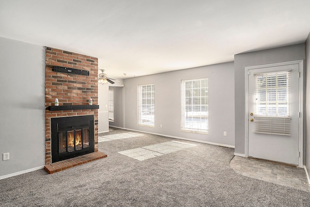 unfurnished living room featuring light carpet, ceiling fan, a brick fireplace, and baseboards