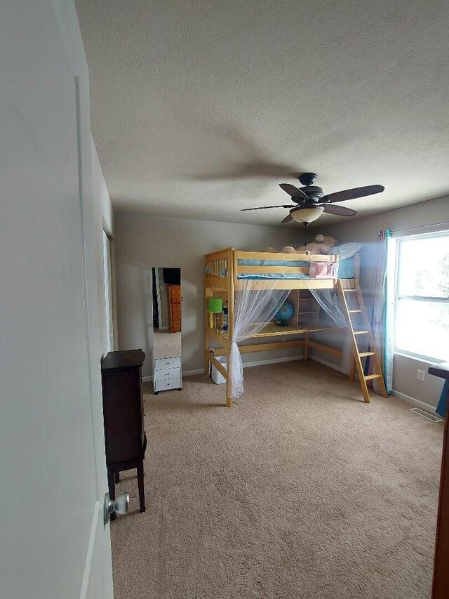 unfurnished bedroom featuring a textured ceiling, ceiling fan, carpet, and baseboards