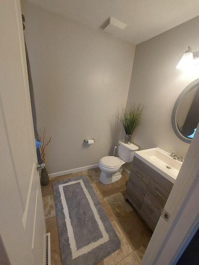 half bathroom featuring toilet, baseboards, visible vents, and vanity