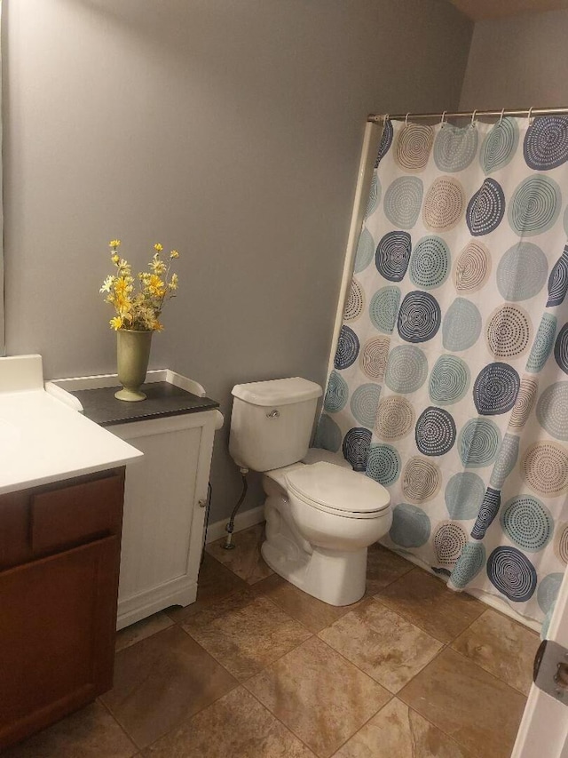 bathroom with toilet, curtained shower, baseboards, and vanity