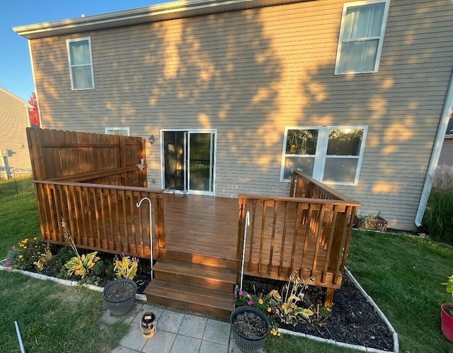 back of property with a deck and a lawn