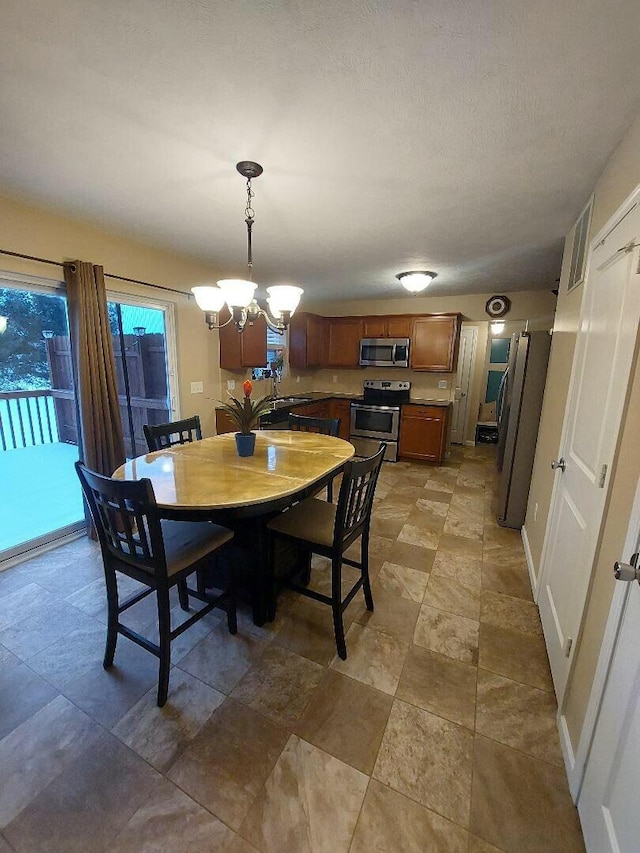 dining area with a chandelier, a textured ceiling, and baseboards