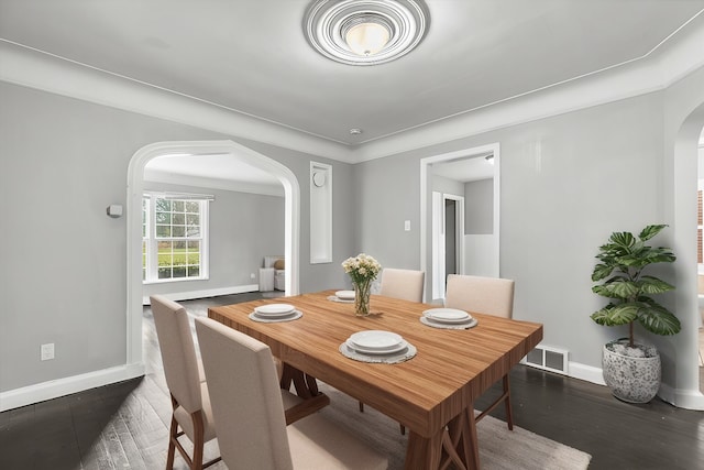 dining space with visible vents, arched walkways, dark wood finished floors, and baseboards