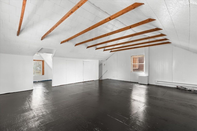 additional living space with a healthy amount of sunlight, vaulted ceiling with beams, and baseboard heating