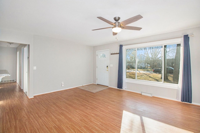 unfurnished living room with a ceiling fan, baseboards, visible vents, and wood finished floors