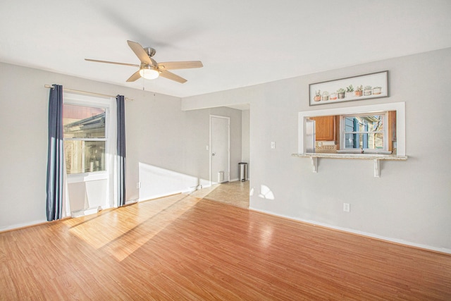 empty room featuring light wood finished floors, ceiling fan, and baseboards