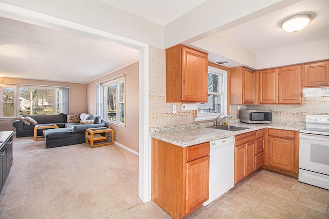 kitchen featuring under cabinet range hood, white appliances, a sink, open floor plan, and backsplash