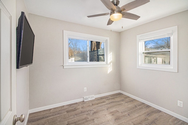 spare room featuring light wood finished floors, visible vents, baseboards, and ceiling fan