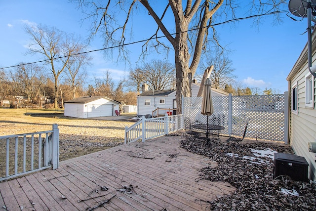 wooden deck with a garage, fence, and an outbuilding