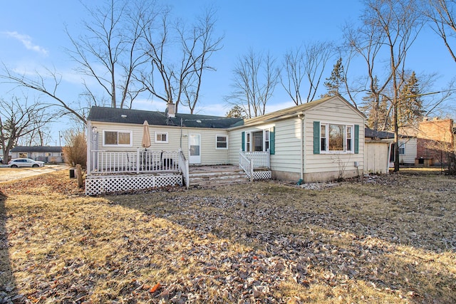 view of front of house featuring a front yard, a chimney, and a wooden deck