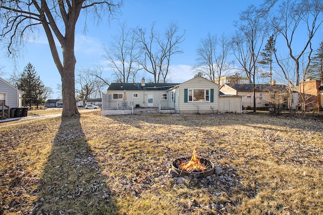 rear view of property featuring an outdoor fire pit and a chimney