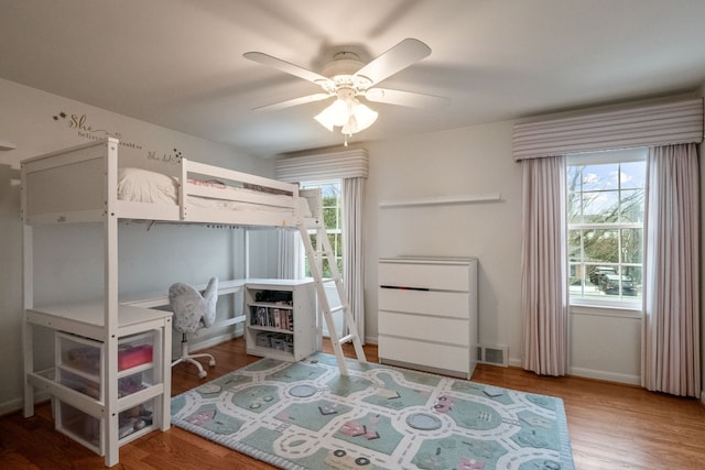 bedroom with a ceiling fan, baseboards, visible vents, and wood finished floors