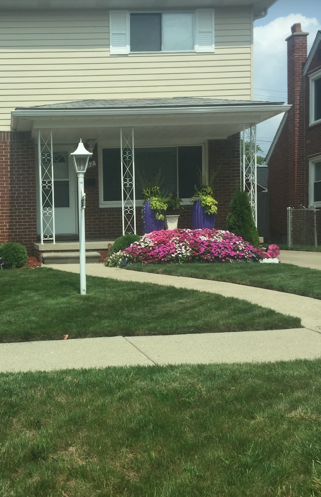 exterior space featuring a porch, a lawn, and brick siding