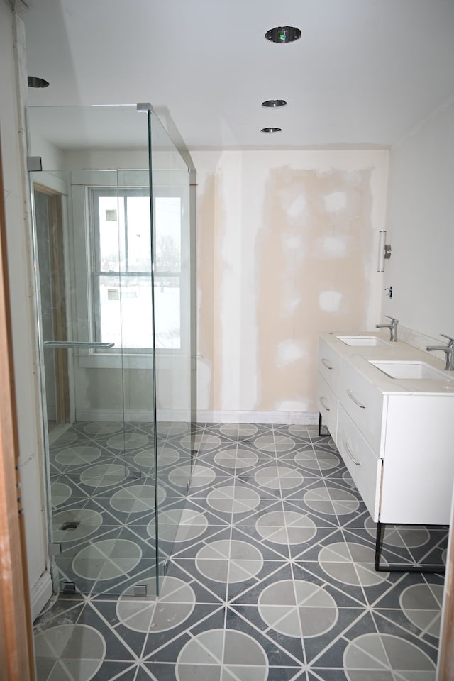 bathroom with double vanity, a stall shower, and a sink