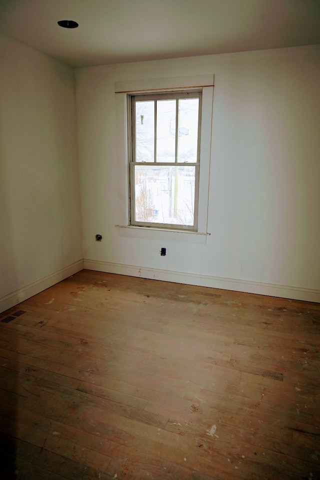 unfurnished room with hardwood / wood-style flooring, visible vents, and baseboards