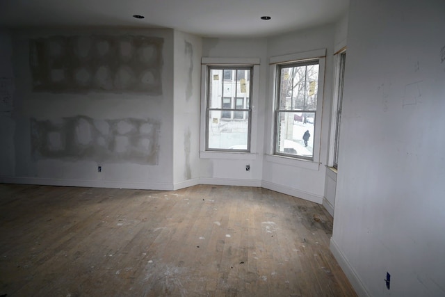 spare room with baseboards and hardwood / wood-style flooring