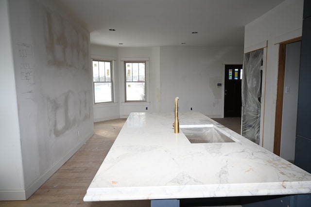 kitchen with a sink, a kitchen island with sink, and light wood-style floors