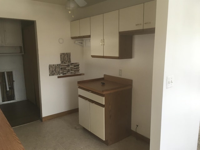 kitchen featuring ceiling fan, cream cabinetry, and baseboards