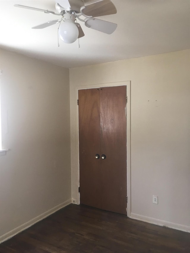 spare room with dark wood-style floors, ceiling fan, and baseboards