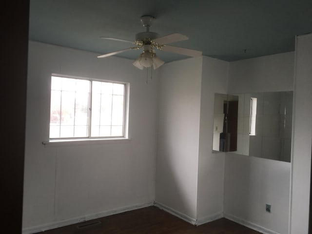 spare room with dark wood-style floors, ceiling fan, visible vents, and baseboards