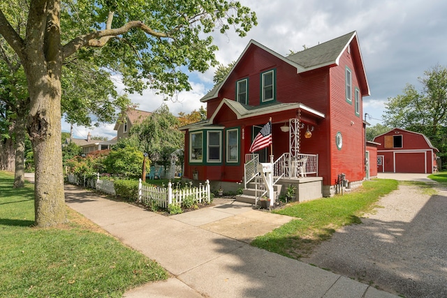 view of front of property featuring a detached garage, a shingled roof, a front yard, fence, and an outdoor structure