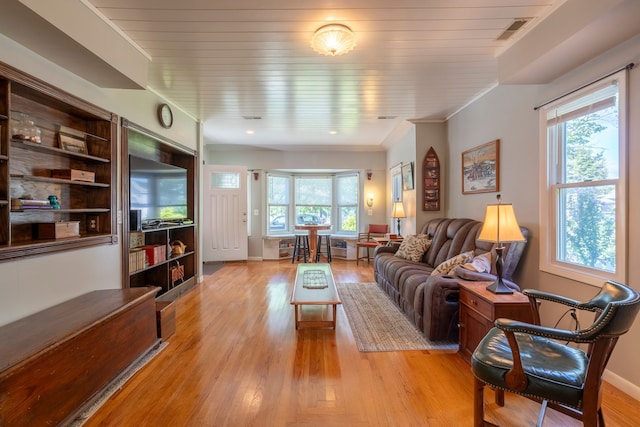 living room with baseboards, light wood-style flooring, visible vents, and a healthy amount of sunlight