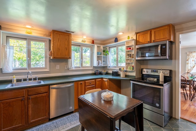 kitchen with dark countertops, brown cabinets, stainless steel appliances, and a sink