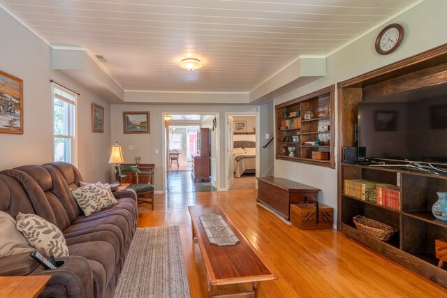 living area featuring crown molding, baseboards, visible vents, and light wood-style floors