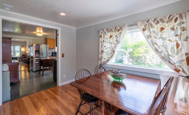 dining room featuring dark wood-style floors, baseboards, visible vents, and crown molding