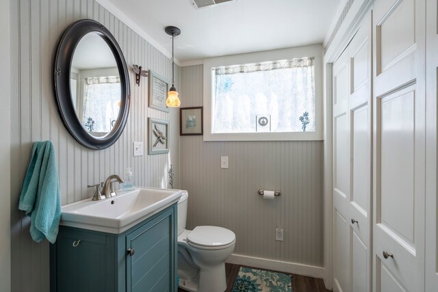 bathroom with visible vents, baseboards, toilet, wood finished floors, and vanity