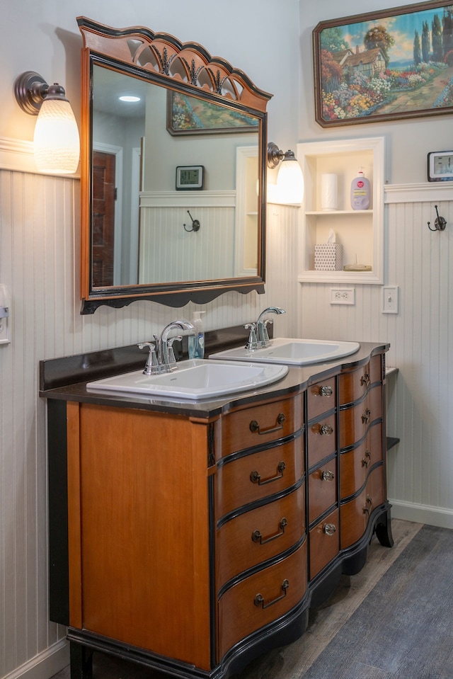 bathroom featuring double vanity, wood finished floors, and a sink